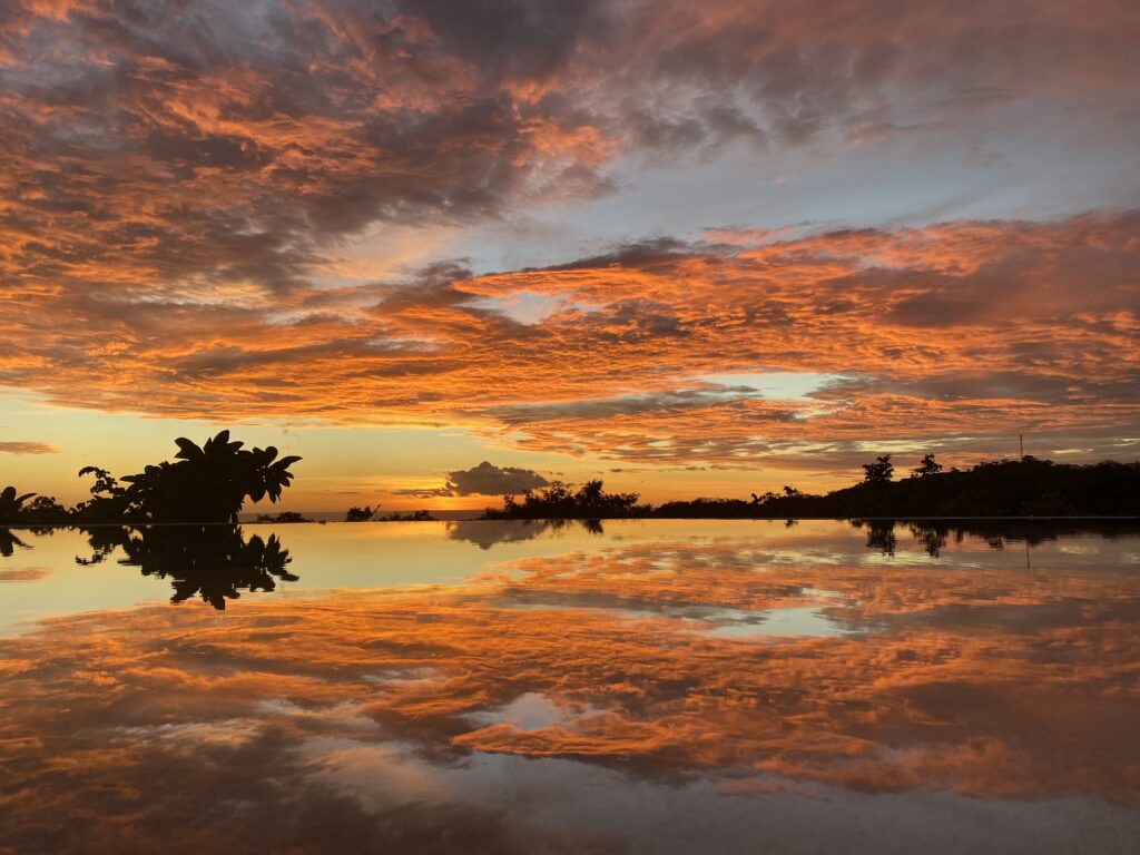 Fiery Pacific sunset reflected in the infinity pool at Pacific Kalokairi in Tamarindo